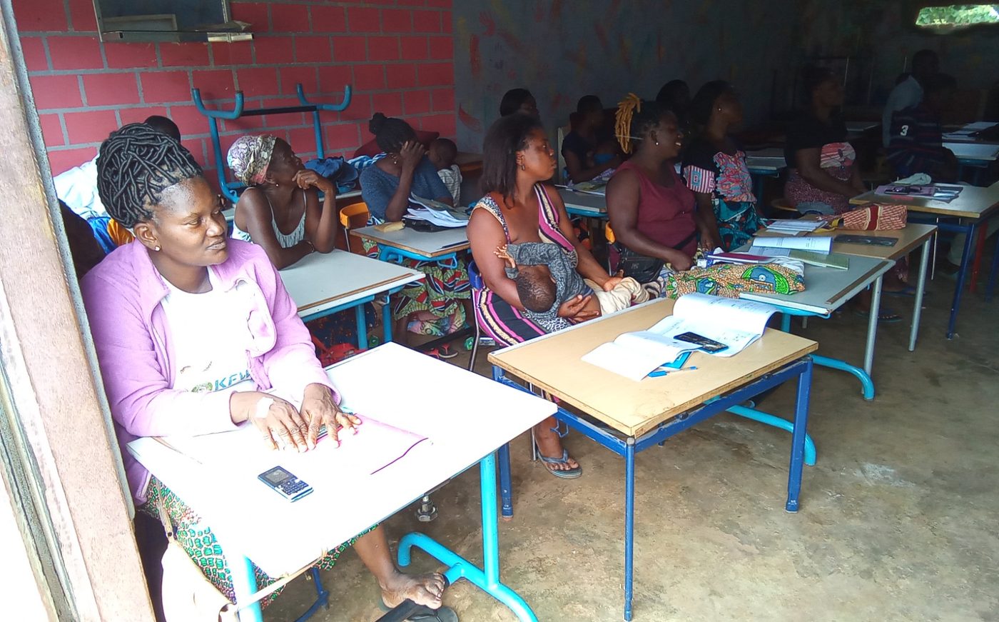 Des apprenantes en plein cours d'alphabétisation dans un centre SSF, cahiers ouverts